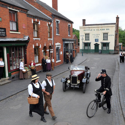 Black Country Living Museum vintage street scene with people in period costumes and an old car.