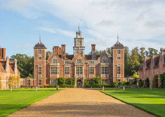Driveway view of Blickling hall  with bright summers sun and green grass. Blickling Hall is a premier 17th-century Jacobean mansion in Norfolk, England, managed by the National Trust. Famous for its red-brick, gabled architecture, it features a 123-foot Long Gallery library, a grand staircase, and a storied history as the likely birthplace of Anne Boleyn. The hall is set within 4,600+ acres of parkland and 55 acres of manicured gardens. 