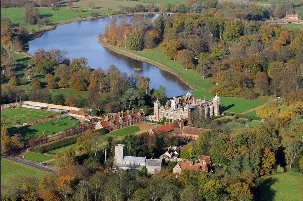 Aerial view of Blickling Hall. Blickling Hall is a premier 17th-century Jacobean mansion in Norfolk, England, managed by the National Trust. Famous for its red-brick, gabled architecture, it features a 123-foot Long Gallery library, a grand staircase, and a storied history as the likely birthplace of Anne Boleyn. The hall is set within 4,600+ acres of parkland and 55 acres of manicured gardens. 