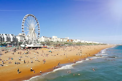 Brighton beach scene with a large Ferris wheel and people enjoying the sun and water. 