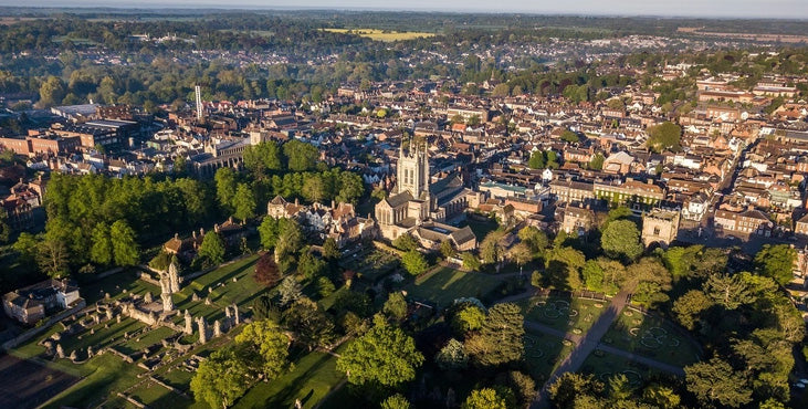 Aerial view of Bury St Edmonds with a prominent cathedral surrounded by greenery. Bury St Edmunds is a historic, charming market town in Suffolk, England, renowned for its medieval architecture, the 1,000-year-old Abbey of St Edmund ruins, and its status as a "foodie capital." It features vibrant, independent shops, the St Edmundsbury Cathedral, and beautiful green spaces like the Abbey Gardens.