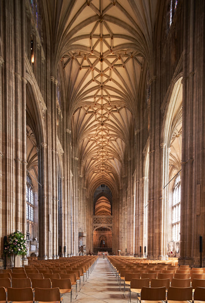 Narrow shot of a Canterbury Cathedral interior with high vaulted ceilings and rows of pews. Canterbury Cathedral's interior is a vast, awe-inspiring mix of Romanesque and Gothic architecture, featuring a high-vaulted perpendicular nave, the historic 12th-century quire, and the tranquil Trinity Chapel. Key features include stunning medieval stained glass, the Martyrdom spot of Thomas Becket, the ancient crypt, and the stone screen with royal statues.