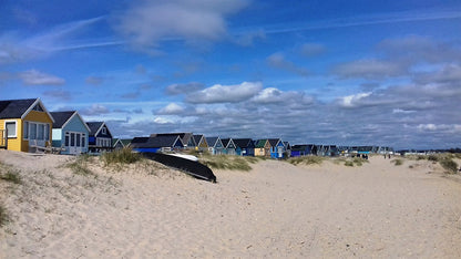 Christchurch beach scene with beach huts on a sandy beach with a clear blue sky