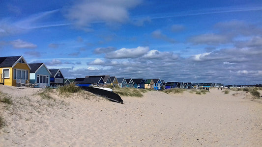 Christchurch beach scene with beach huts on a sandy beach with a clear blue sky