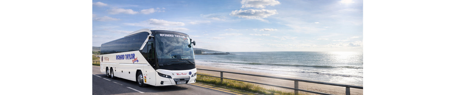 Richard Taylor Travels Coach on a road with a scenic ocean view in the background