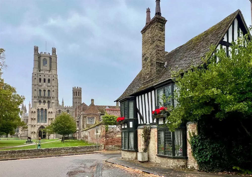 Traditional English cottage with a Ely Cathedral in the background. Ely Cathedral, known as the "Ship of the Fens," is a stunning 11th-century Romanesque and Gothic masterpiece in Cambridgeshire, famed for its unique Octagon Tower, long nave, and vibrant stained glass. The compact city centre, surrounding the cathedral, features historic streets, Oliver Cromwell’s House, and a bustling market, offering a charming mix of medieval history and modern amenities.
