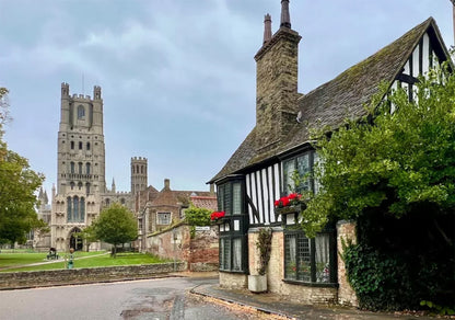 Traditional English cottage with a Ely Cathedral in the background. Ely Cathedral, known as the "Ship of the Fens," is a stunning 11th-century Romanesque and Gothic masterpiece in Cambridgeshire, famed for its unique Octagon Tower, long nave, and vibrant stained glass. The compact city centre, surrounding the cathedral, features historic streets, Oliver Cromwell’s House, and a bustling market, offering a charming mix of medieval history and modern amenities.