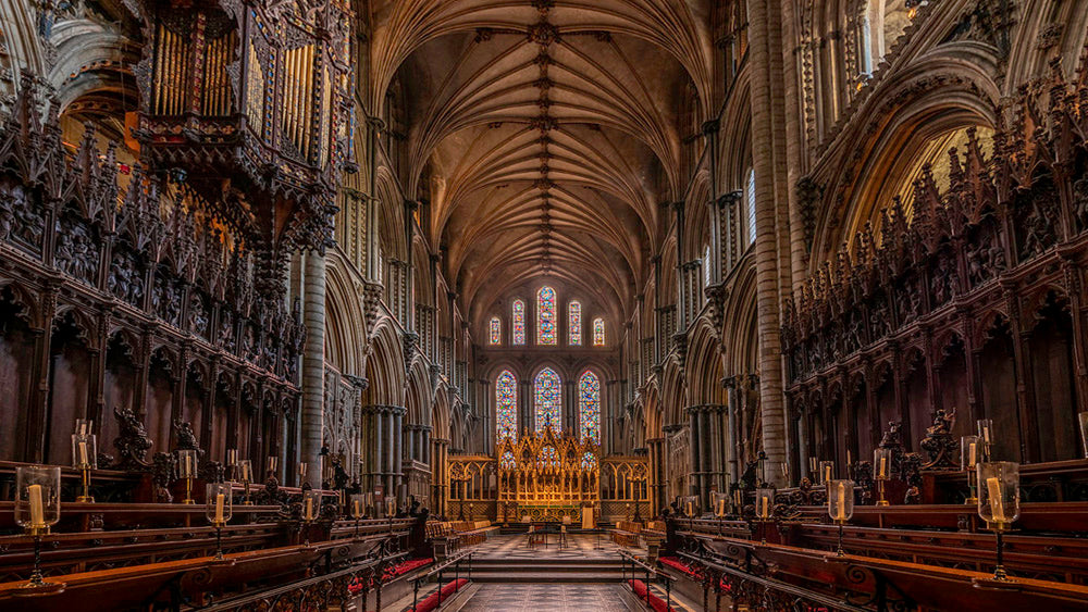 Nave of Ely Cathedral with high vaulted ceilings and stained glass windows. Ely Cathedral, known as the "Ship of the Fens," is a stunning 11th-century Romanesque and Gothic masterpiece in Cambridgeshire, famed for its unique Octagon Tower, long nave, and vibrant stained glass. The compact city centre, surrounding the cathedral, features historic streets, Oliver Cromwell’s House, and a bustling market, offering a charming mix of medieval history and modern amenities.