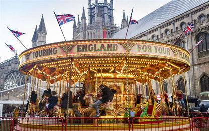 Carrousel with 'Touring England For Your Pleasure' sign in front of Ely cathedral at their famous Christmas Fair. 