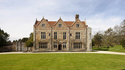 Large stone manor house of Greys Court with a red roof on a clear day. Greys Court is a picturesque 16th-century Tudor manor house located near Henley-on-Thames, Oxfordshire, surrounded by 280 acres of stunning gardens and woodland. Owned by the National Trust, it is renowned for its romantic, intimate atmosphere, featuring medieval ruins, colourful walled gardens, a 12th-century tower, and a rare Tudor donkey wheel.