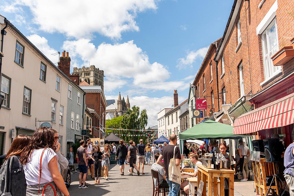 People walking along Norwich lanes with shops and Norwich Cathedral in the background on a sunny day. The Norwich Lanes are a charming, largely pedestrianized area in Norwich city centre, featuring a dense network of medieval alleyways, Georgian streets, and over 300 independent retailers, cafés, pubs, and restaurants. Known for its unique, bohemian atmosphere, this vibrant cultural hub offers a mix of specialty shops, live music venues, cinemas, and galleries.