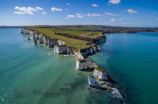 Aerial view of Poole coastal landscape with cliffs and greenery. Old Harry Rocks are a famous series of white chalk sea stacks and stumps located at Handfast Point, on the Isle of Purbeck in Dorset, southern England, near Poole and Studland Bay. They mark the most eastern point of the Jurassic Coast,