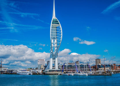 Spinnaker Tower with a blue sky and water in the foreground. The Spinnaker Tower is a 170-metre landmark observation tower in Portsmouth, England. It is the centrepiece of the redevelopment of Portsmouth Harbour, which was supported by a National Lottery grant.