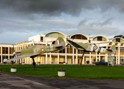 Vintage Spitfire airplanes on display in front of RAF Hendon with a cloudy sky. The Royal Air Force Museum London (RAF Hendon) is a free, family-friendly museum in North London, located on the historic former London Aerodrome. It features over 100 aircraft across multiple hangars, interactive galleries, and exhibits documenting the history of aviation, the Battle of Britain, and the RAF’s centenary.