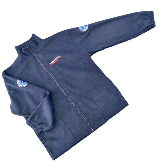 Richard Taylor Travel navy blue zip-up fleece jacket with a stand collar, elastic cuffs, and pockets, featuring a small red and white embroidered logo on the left chest and a circular blue and white patch on the sleeve.
