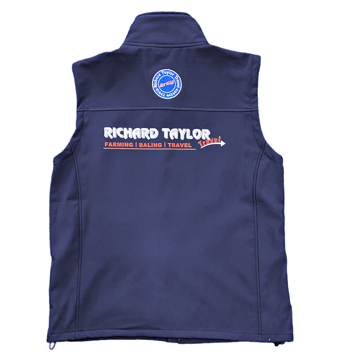 Richard Taylor Travel navy blue sleeveless soft shell vest shown from the back, featuring a circular blue and white logo near the top center and a large 'RICHARD TAYLOR TRAVEL' text graphic with 'FARMING | BALING | TRAVEL' and a red arrow in white and red below it.
