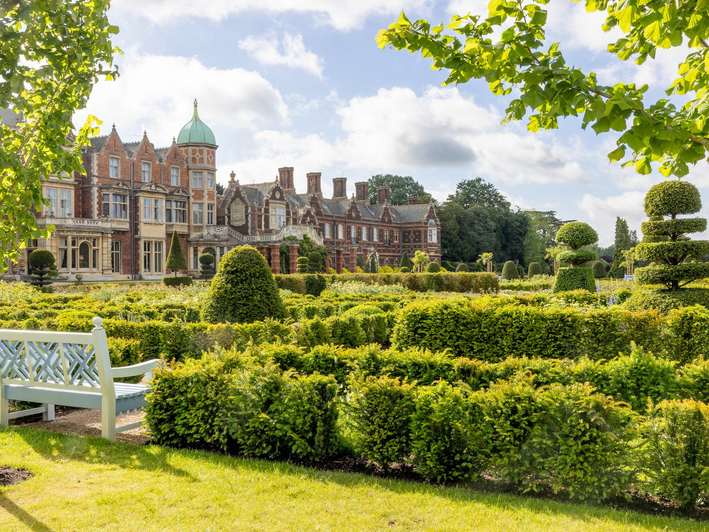 Sandringham Estate with manicured gardens and a clear blue sky. Sandringham Estate is a 20,000-acre Norfolk country estate and private home to British monarchs since 1862. Famed as the Royal Family's Christmas retreat, it features Sandringham House (circa 1870), 60 acres of gardens, the St Mary Magdalene Church, and extensive public woodland. The estate is a working, sustainable landscape within the Norfolk Coast Area of Outstanding Natural Beauty. 