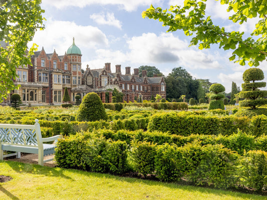 Sandringham Estate with manicured gardens and a clear blue sky. Sandringham Estate is a 20,000-acre Norfolk country estate and private home to British monarchs since 1862. Famed as the Royal Family's Christmas retreat, it features Sandringham House (circa 1870), 60 acres of gardens, the St Mary Magdalene Church, and extensive public woodland. The estate is a working, sustainable landscape within the Norfolk Coast Area of Outstanding Natural Beauty. 