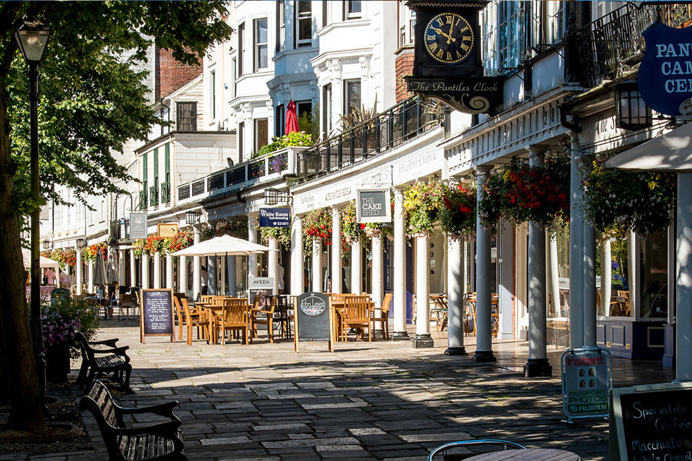 Royal Tunbridge Wells Street scene with shops, tables, and chairs in a town setting. Royal Tunbridge Wells is a fashionable historic spa town in Kent, southeast England, renowned for its Georgian architecture, the colonnaded Pantiles, and the 17th-century Chalybeate Spring. Located under an hour from London, it offers a mix of high-street shopping, independent boutiques, scenic parks, and upscale dining.