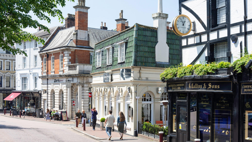 Royal Tunbridge Wells Town street scene with historic buildings, a clock tower, and people walking. Royal Tunbridge Wells is a fashionable historic spa town in Kent, southeast England, renowned for its Georgian architecture, the colonnaded Pantiles, and the 17th-century Chalybeate Spring. Located under an hour from London, it offers a mix of high-street shopping, independent boutiques, scenic parks, and upscale dining.