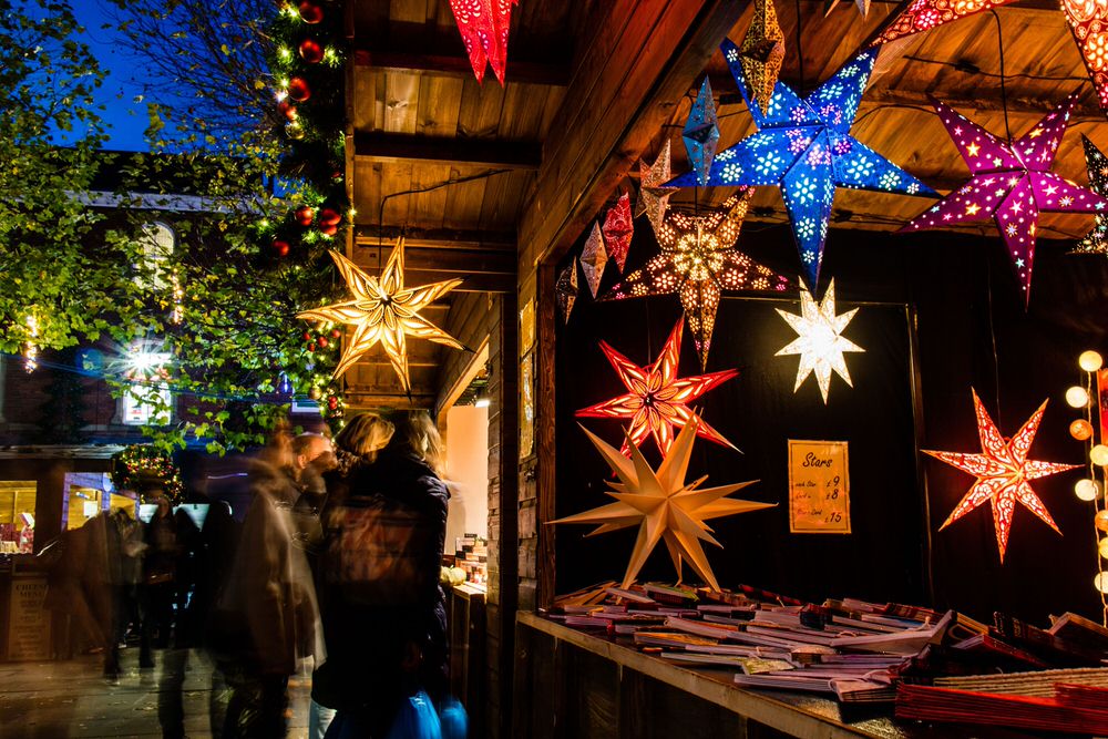 Decorative star lights hanging from a wooden shop roof at York festive market.